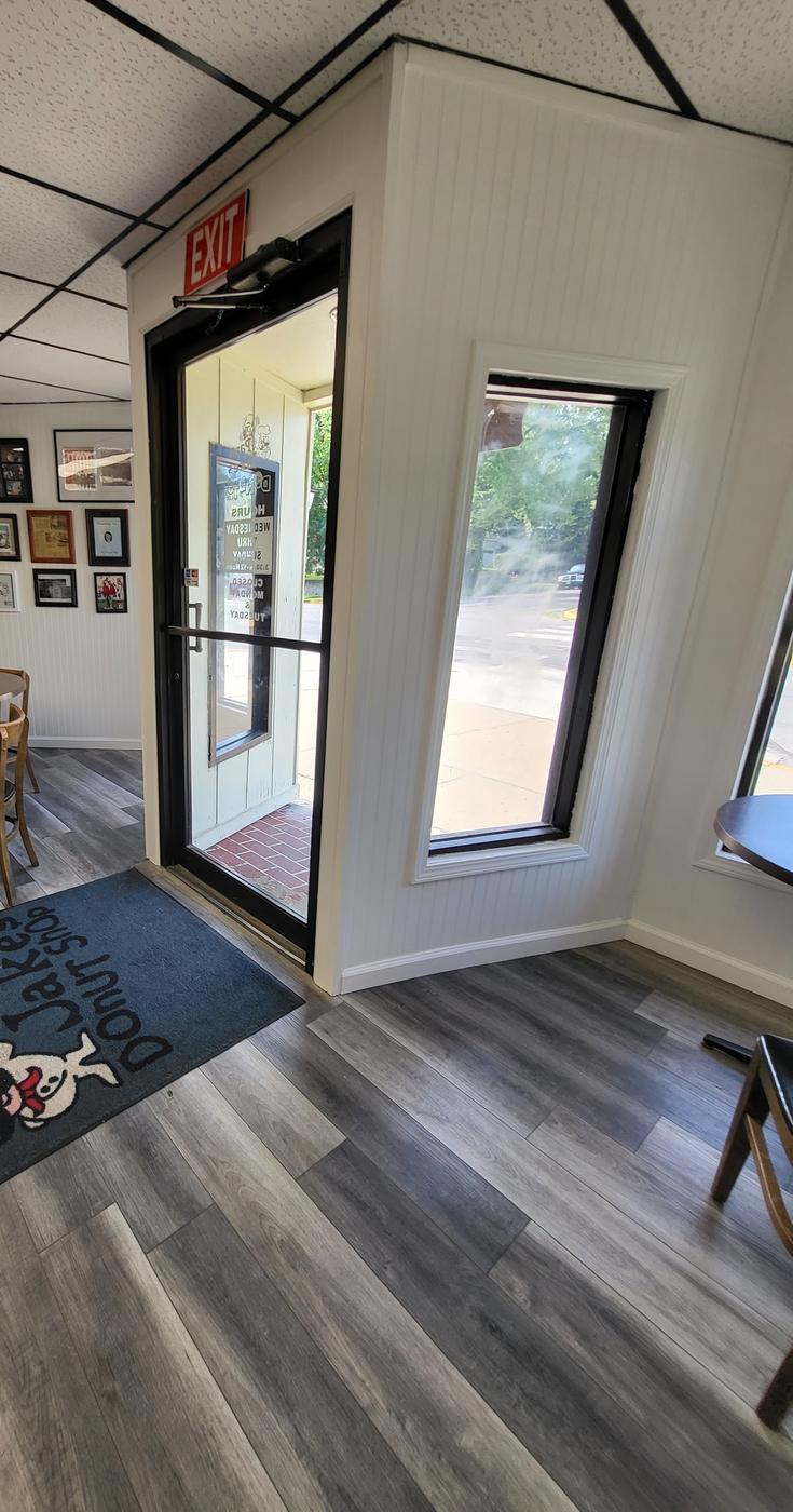 Inside Papa Jake's: the glass front door with the hours decal, a Papa Jake's floor mat and a wall of framed photographs.
